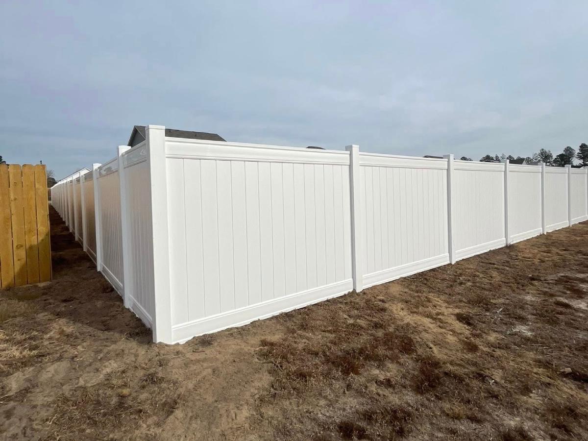 White vinyl privacy fence corner installation on new construction lot with clean panel lines in Fayetteville, NC